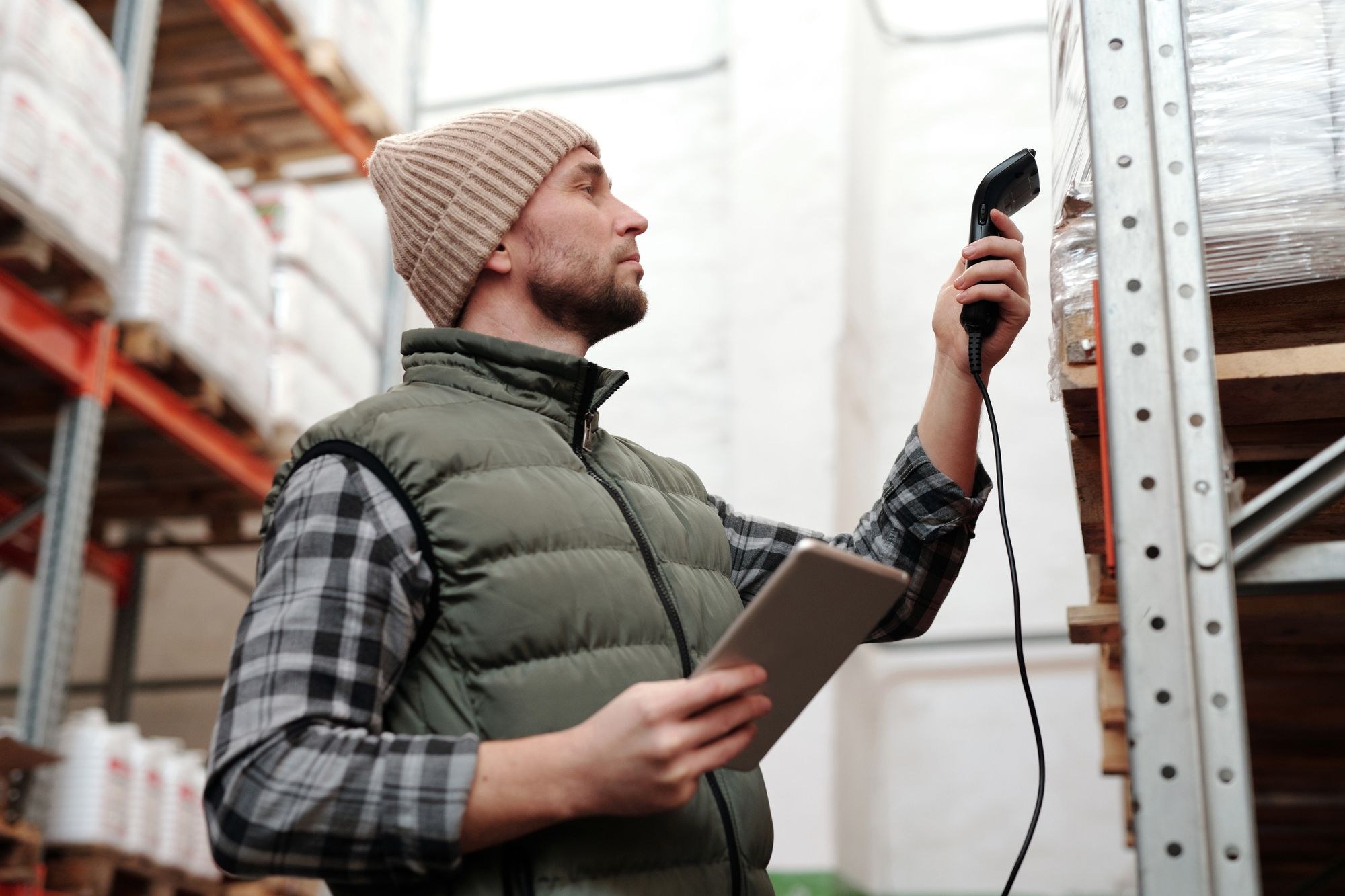 Warehouse employee checking inventory with a handheld scanner and tablet